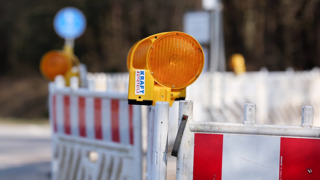 Baustellenbaken und Absperrzaun stehen am Straßenrand.