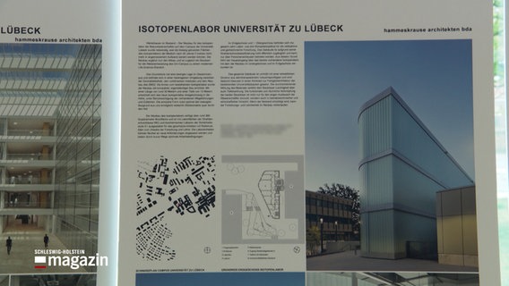 Auf einem Plakat ist ein Gebäude abgebildet mit der Überschrift "Isotopenlabor Universität zu Lübeck". © NDR 