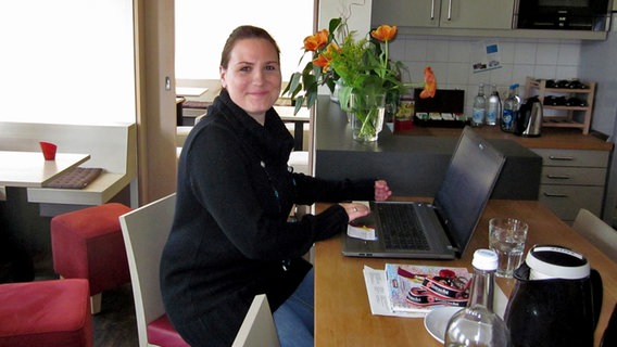Eine junge Frau sitzt mit Laptop an einem Tisch © NDR Foto: Linn Mackenzie