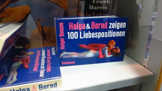In einer Vitrine stehen Exemplare des Buches "Helga&Bernd zeigen 100 Liebespositionen". © NDR Foto: Peer-Axel Kroeske