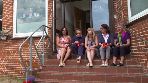 Einige Frauen sitzen auf den Eingangsstufen des Begegnungszentrums Lauenburg. © NDR 