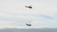 An einem Hubschrauber hängt ein geborgendes Flugzeug. © NDR 