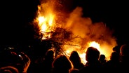 Mehrere Menschen stehen vor den lodernden Flammen eines Biikefeuers in Tönning. © NDR Foto: Jörn Schaar