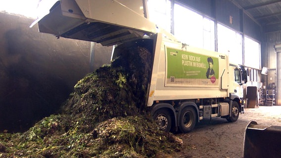 Ein Mülllaster entlädt Biomüll in einer Halle auf einen Haufen. © NDR 