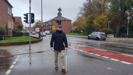 Dieter Engelhardt überquert mit seinem Blindenstock die grüne Fußgängerampel an der Ludwig-Nissen-Straße in Husum.  Foto: Peer-Axel Kroeske
