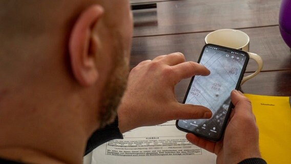 Fatih Onur schaut auf sein Handy - darin ein Foto von der Verdachtsstelle des Blindgängers. © NDR Foto: Thomas Viet Dang