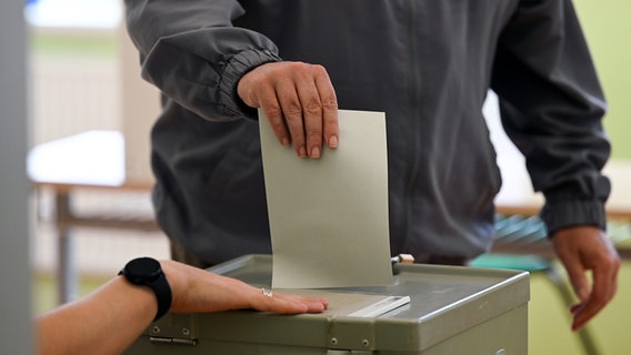 Ein Mann wirft seinen Stimmzettel bei einer Wahl in eine Wahlurne (Themenbild). © picture alliance/dpa Foto: Robert Michael