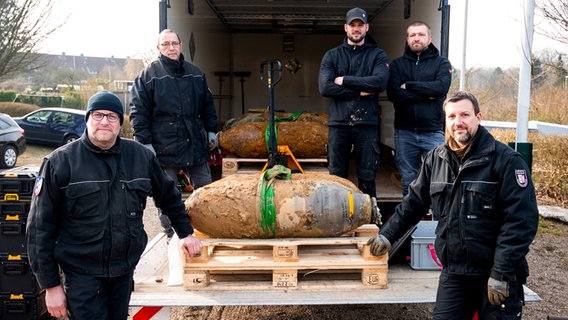 Einsatzkräfte des Kampfmittelräumdienstes zeigen sich mit mehreren entschäften Bomben. © dpa Foto: Daniel Bockwoldt
