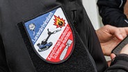 Ein Patch mit der Aufschrift "Landeskriminalamt, Kampfmittelräumdienst Schleswig-Holstein" ist auf der Jacke eines Bombenentschärfers zu sehen. © picture alliance Foto: Markus Scholz