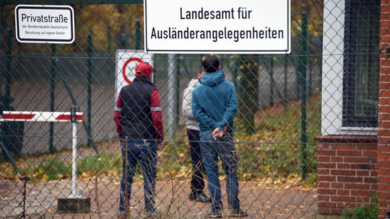 Bewohner stehen in Boostedt am Zugang zu der Erstaufnahmeeinrichtung. © dpa-Bildfunk Foto: Carsten Rehder