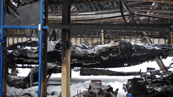 Abbildung zeigt eine abgebrannte Bootshalle in der die Überreste von Jachten zu erkennen sind. © NDR Foto: Hauke von Hallern