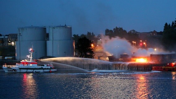 Von einem Rettungskreuzer aus bekämpfen Helfer in der Nacht zu Freitag den Brand in einem Tanklager in Kiel. ©  dpa - Report Foto: Carsten Rehder