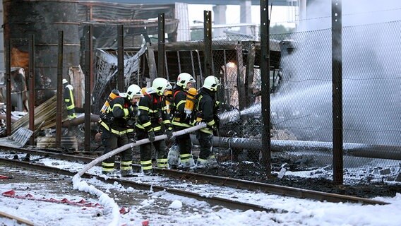 Feuerwehrmänner löschen in der Nacht zu Freitag nach dem Brand in einem Tanklager in Kiel letzte Glutnester. ©  dpa - Report Foto: Carsten Rehder
