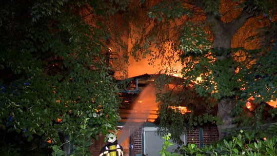 Eine Einsatzkraft der Feuerwehr löscht ein brennendes Fachwerkhaus in Glinde. © TeleNewsNetwork 