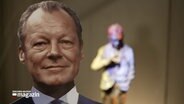 Ein Aufsteller und eine Statue von Willy Brandt. © NDR 