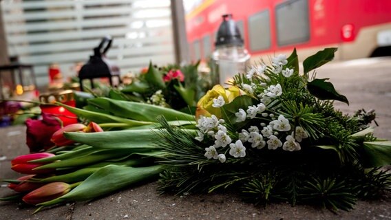 Kerzen und Blumen stehen und liegen im Bahnhof Brokstedt in einem Wartehäuschen. Bei einer Messerattacke in einem Regionalzug von Kiel nach Hamburg waren am 25.01.2023 in Brokstedt zwei junge Menschen getötet und weitere verletzt worden. © picture alliance/dpa Foto:  Daniel Bockwoldt