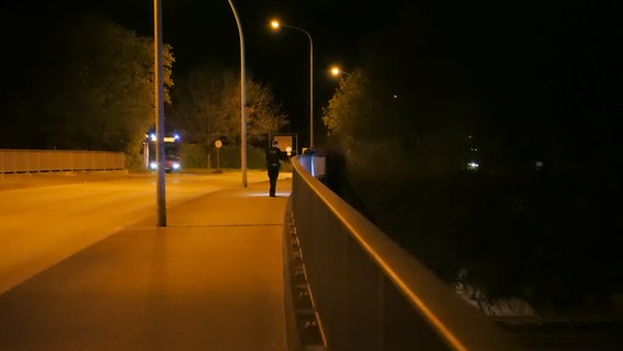 Ein Polizist geht im Dunkeln über eine Brücke.  © Daniel Friederichs Foto: Daniel Friederichs