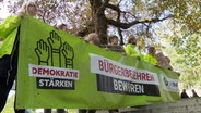 Menschen der Volksinitiative stehen mit einem Banner vor dem Kieler Landeshaus. © NDR 