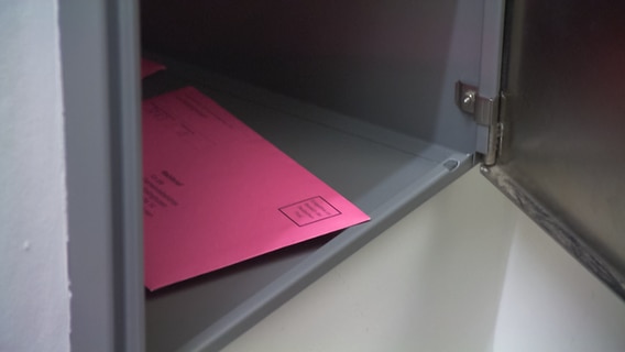 Ein Briefumschlag in Farbe rosa liegt in einem Briefkasten im Amt Kellinghusen. © NDR 
