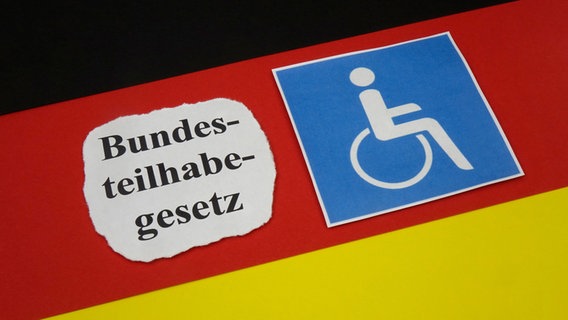 Auf einer Deutschlandfahne liegt der Schriftzug Bundesteilhabegesetz und ein Behindertensymbol. © picture alliance/dpa-Zentralbild Foto: Sascha Steinach