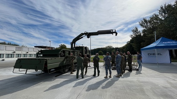 Ein Werkstattwagen der Bundeswehr steht mit einem ausgefahrenen Kran neben einer Gruppe von menschen. © NDR Foto: Christoph Deuschle