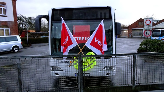 Ein Bus mit zwei Verdi-Flaggen und einer Warnweste geschmückt steht auf einem Parkplatz in Flensburg. © NDR Foto: Peer-Axel Kroeske
