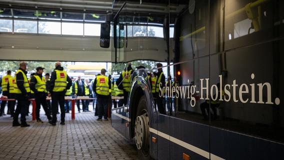 Einige Menschen stehen neben einem Bus. Diese Menschen tragen gelbe Warn·westen. Die Menschen streiken nämlich. © dpa Bildfunk Foto: Hannes P. Albert
