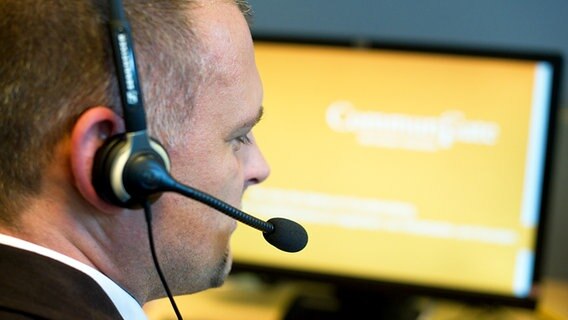 Ein Callcentermitarbeiter sitzt vor einem PC Monitor und hat ein Headset auf dem Kopf © dpa Picture Alliance Foto: Patrick Pleul