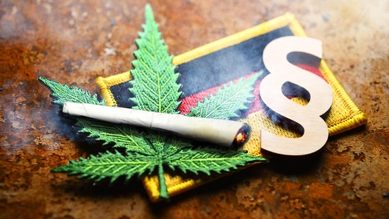 Eine Fotomontage mit Cannabisblatt-Symbol, Joint und Paragrafenzeichen auf Deutschlandfahne, © picture alliance Foto: Christian Ohde