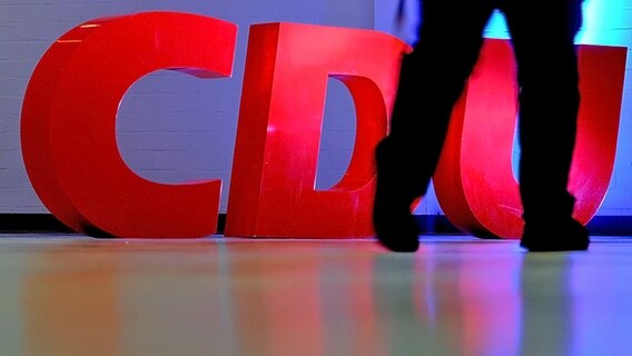 Ein Parteimitglied geht an dem CDU-Logo vorbei © picture alliance / dpa Foto: Angelika Warmuth