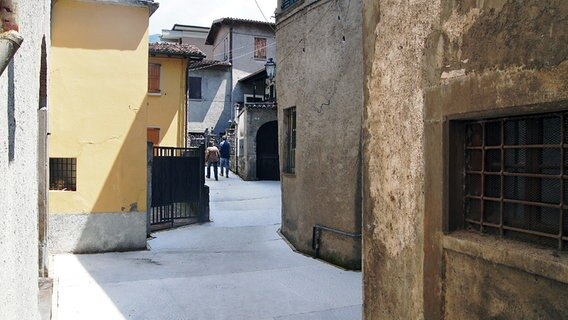 Zwei Menschen gehen durch eine Gasse in einer italienischen Stadt. © NDR Foto: Hauke von Hallern / Julian Marxen