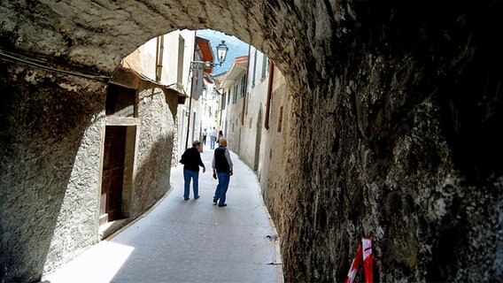 Menschen gehen durch eine Gasse in Italien. © NDR Foto: Hauke von Hallern / Julian Marxen
