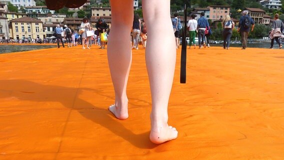 Ein Paar nackter Füße laufen über die "Floating Piers" von Christo. © NDR Foto: Julian Marxen und Hauke von Hallern
