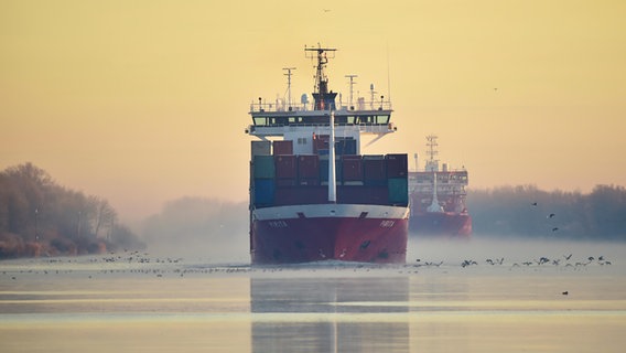 Containerschiff und Frachtschiff bei Sonnenaufgang und Nebel im Nord-Ostsee-Kanal von Schleswig-Holstein. © picture alliance / imageBROKER Foto: Klaus-Dieter Möbus