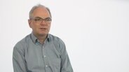 Virologe Dr. Helmut Fickenscher wird vor einem weißen Hintergrund befragt. © NDR 