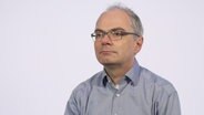 Virologe Dr. Helmut Fickenscher wird vor einem weißen Hintergrund befragt. © NDR 