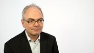 Virologe Dr. Helmut Fickenscher wird vor einem weißen Hintergrund befragt. © NDR Foto: Janis Röhlig