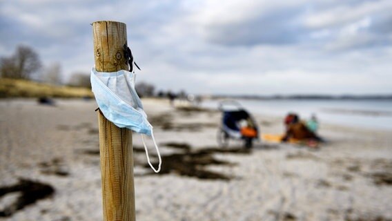 Schutzmaske an einem Holzpfeiler am Strand von Scharbeutz. © Imago Images / Christian Ohde Foto: Christian Ohde