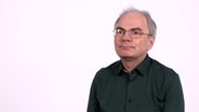 Virologe Dr. Helmut Fickenscher sitzt vor einem weißen Hintergrund in einem Studio. © NDR 