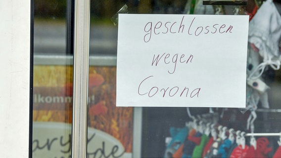 An der Eingangstür eines Geschäfts hängt ein Zettel mit der Aufschrift "geschlossen wegen Corona". © dpa Foto: Patrick Leul