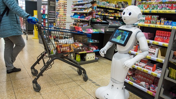 Ein Roboter mit dem Namen Pepper steht in einem Supermarkt vor den Kassen. © dpa-Bildfunk Foto: Daniel Bockwoldt/dpa