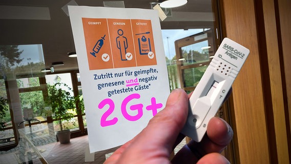 Eine Hand hält einen negativen Corona-Schnelltest vor einer Glastür eines Tagungshotels mit dem Schild "ZUTRITT NUR FÜR GEIMPFTE, GENESENE UND GETESTETE GÄSTE." © IMAGO / Sven Simon Foto: Sven Simon