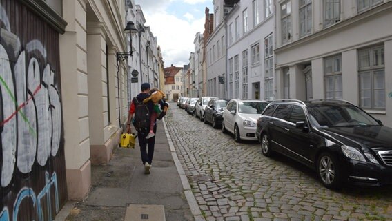 Moritz Tovar läuft mit seiner Tochter durch die Lübecker Altstadt. © NDR Foto: Anne Passow