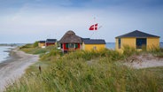 Gelbe und rote Ferienhäuser stehen am Meer in Dänemark. © imago images Foto: Dirk Hinz