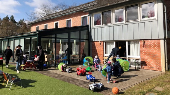 Kinder spielen mit ihren Müttern im Garten eines Hauses. © Hauke von Hallern Foto: Hauke von Hallern