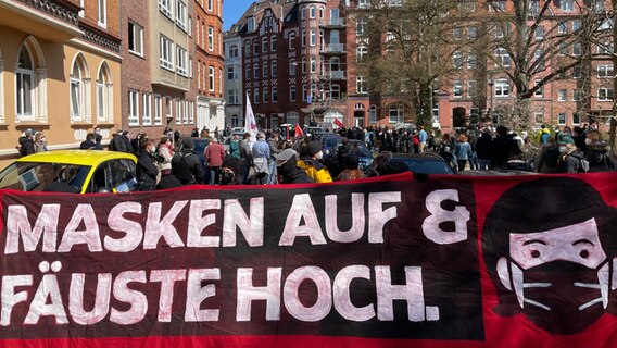 Demonstranten versammeln sich zu einer Demo auf dem Adolfplatz in Kiel gegen die Querdenker-Demo und tragen einen roten Banner mit dem Schriftzug "Masken auf & Fäuste hoch.". © NDR Foto: Christian Wolf