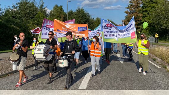Ein Demonstrationszug marschiert über eine Straße. © NDR Foto: Christian Nagel