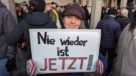 Eine Frau blickt in die Kamera bei einer Demonstration gegen Rechtsextremismus auf dem Lübecker Rathausplatz und hält ein Plakat mit dem Schriftzug "Nie wieder ist jetzt" in ihren Händen. © NDR Foto: Phillip Kamke