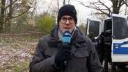 Ein NDR-Reporter steht in einem Wald in der Nähe eines Leichenfunortes bei Kaltenkichen. © NDR 