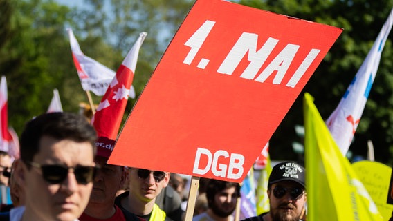 Demonstrierende halten ein selbst gebasteltes Schild mit der Aufschrift "1. Mai DGB" in die Höhe. © picture alliance/dpa Foto: Christoph Soeder